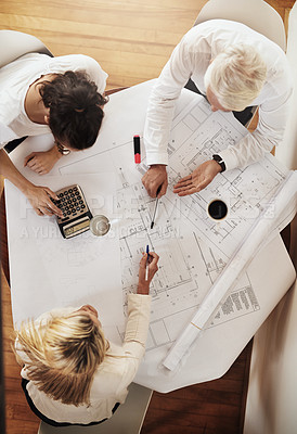 Buy stock photo High angle shot of a group of architects working together on blueprints of a house around a table inside of a building
