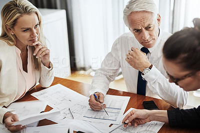 Buy stock photo Shot of a group of architects working together on blueprints of a house around a table inside of a building