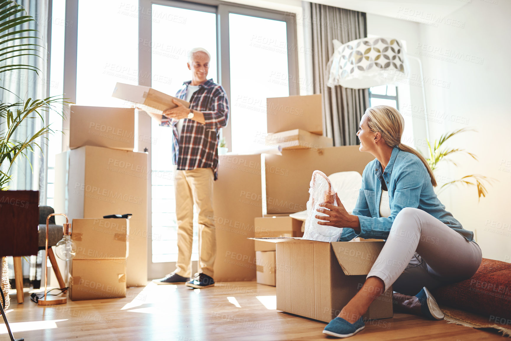 Buy stock photo Real estate, property and a senior couple moving house while packing boxes together in their home. Box, investment and retirement with old people unpacking in the living room of their new apartment