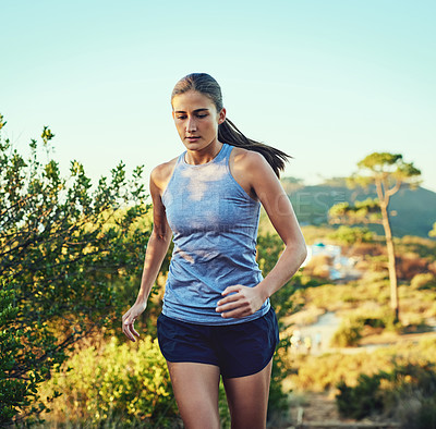 Buy stock photo Shot of a young woman out for a run along a mountain trail