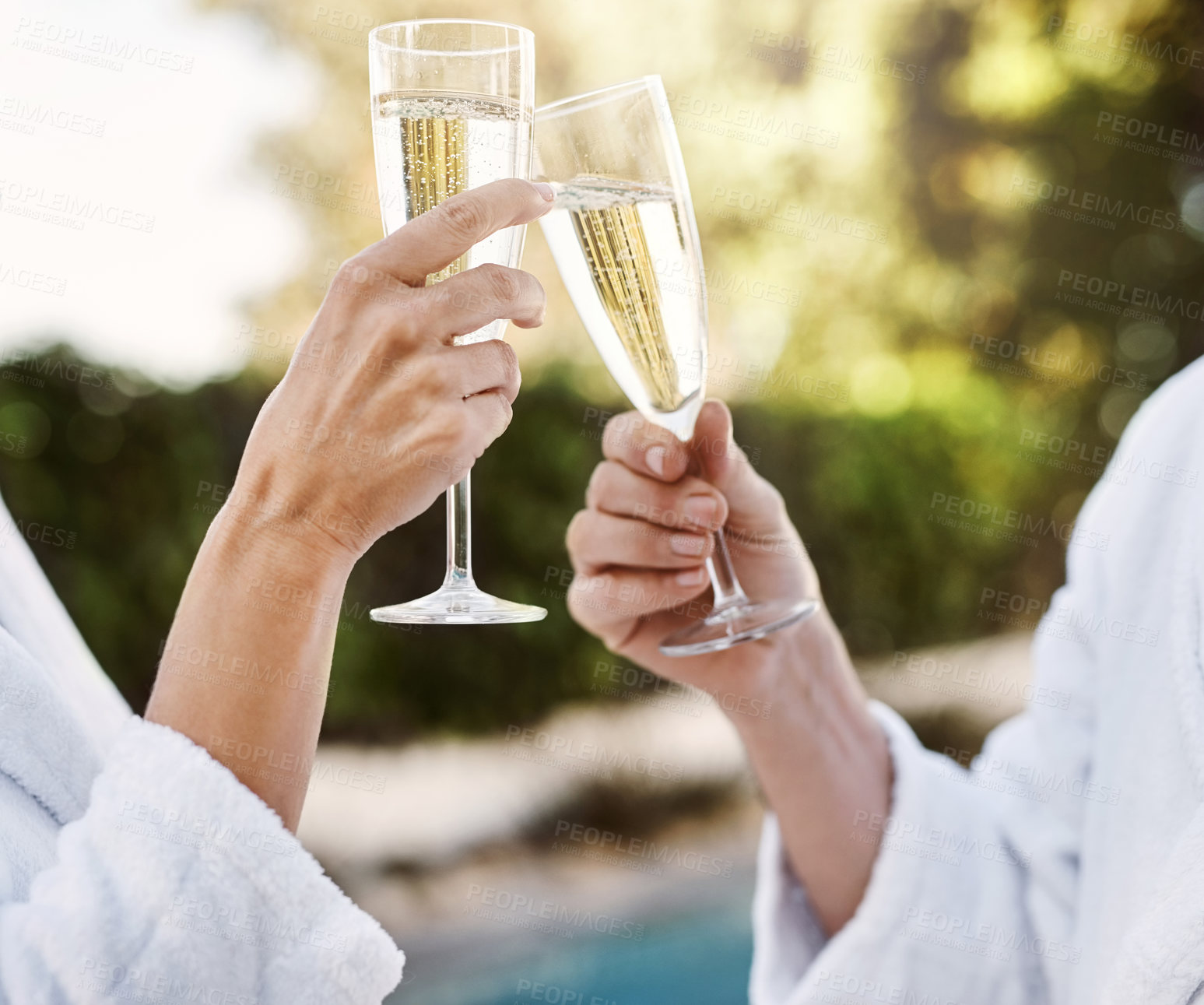 Buy stock photo Shot of two unrecognizable people having a celebratory toast with champagne outside during the day