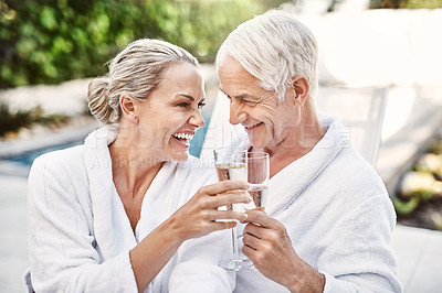 Buy stock photo Shot of a cheerful middle aged couple having a celebratory toast with champagne outside during the day