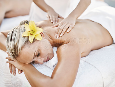 Buy stock photo Shot of a relaxed middle aged woman lying on her stomach while receiving a massage at a spa outside during the day