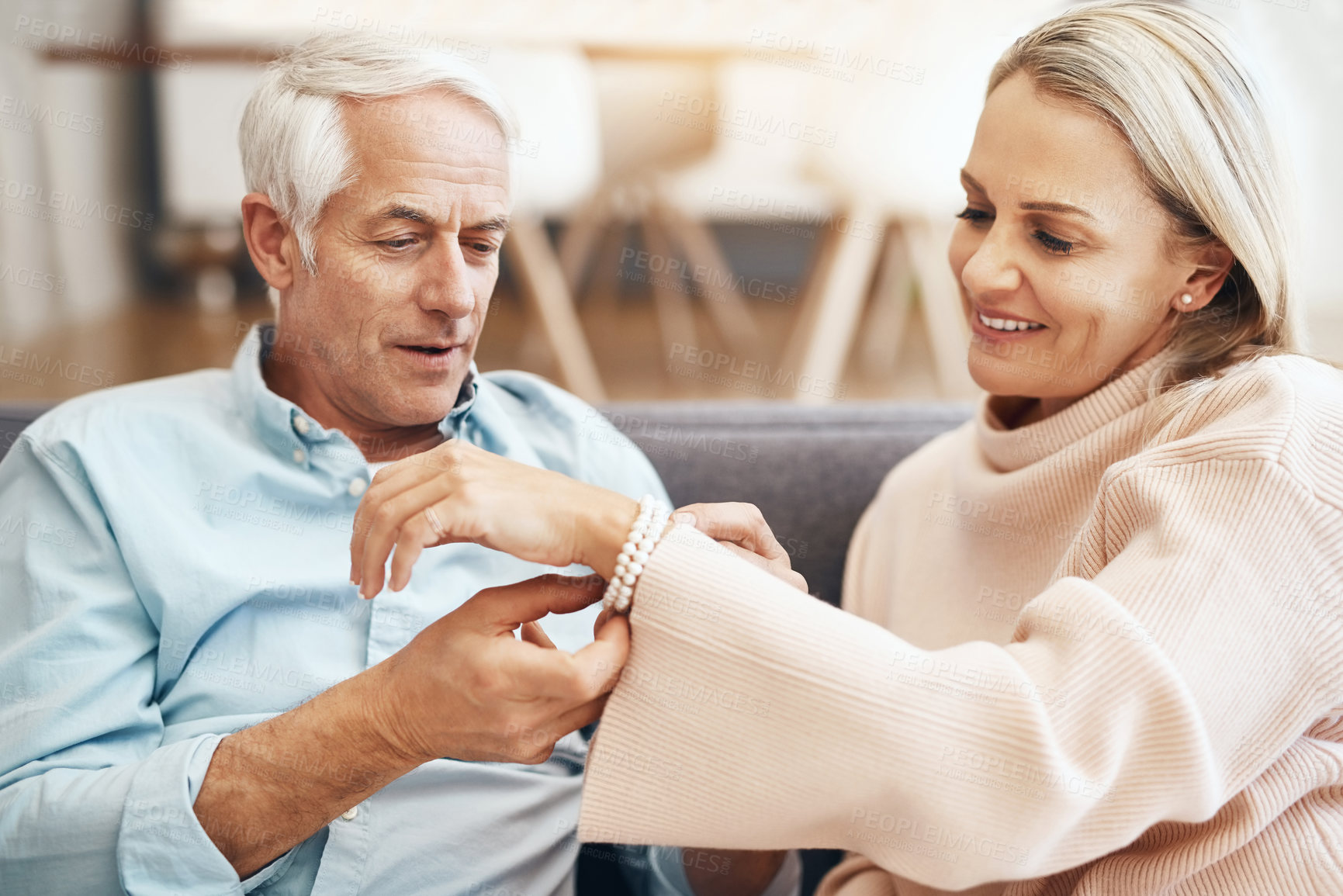Buy stock photo Cropped shot of mature man giving his wife a gift on the sofa at home