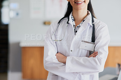 Buy stock photo Cropped shot of an unrecognizable female doctor standing with her arms folded in a hospital