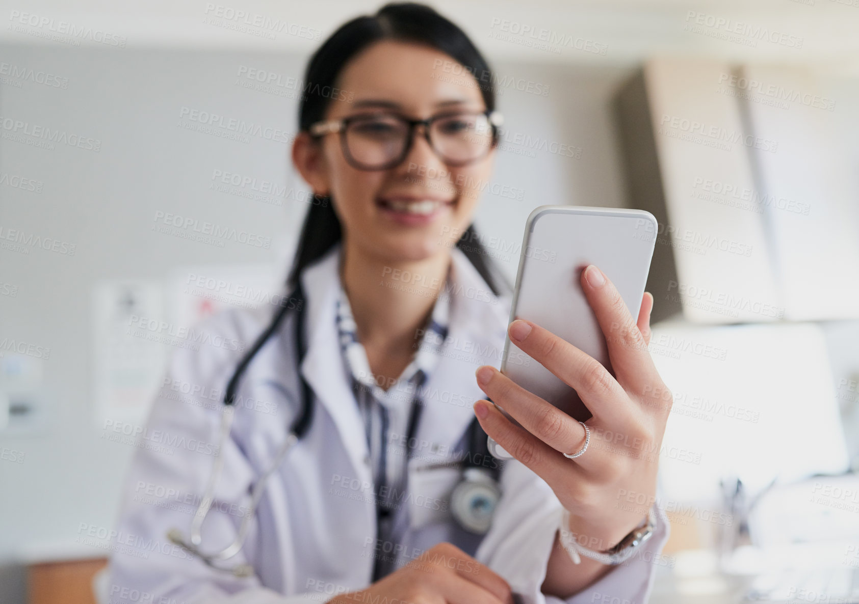 Buy stock photo Cropped shot of a young female doctor sending a text while working in the hospital