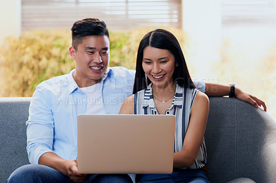 Buy stock photo Shot of a happy young couple using a laptop together on the sofa at home