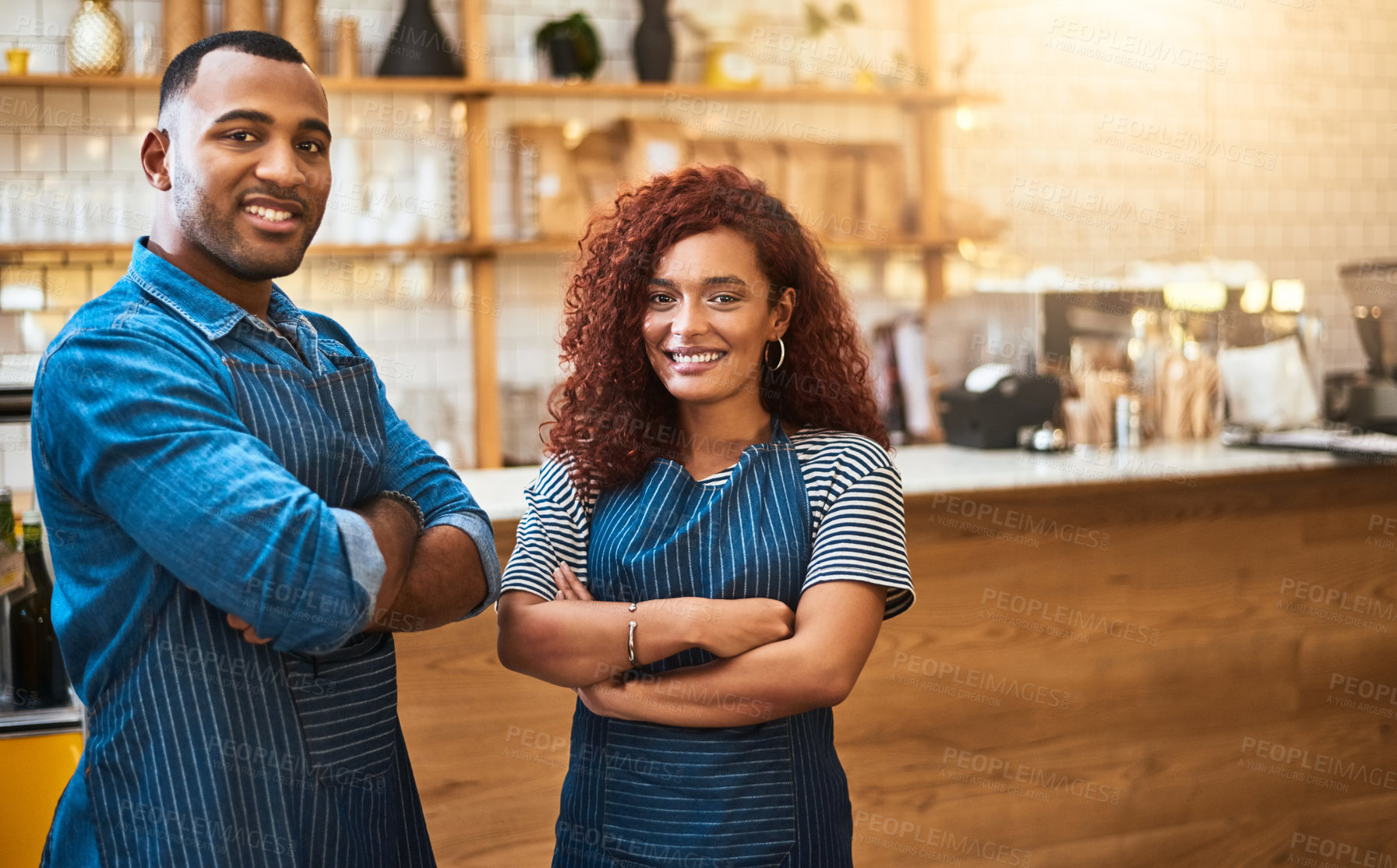 Buy stock photo Cropped portrait of an affectionate young couple standing with their arms crossed in their coffee shop