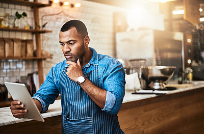 Buy stock photo Cropped shot of a handsome young man working on a tablet in his coffee shop