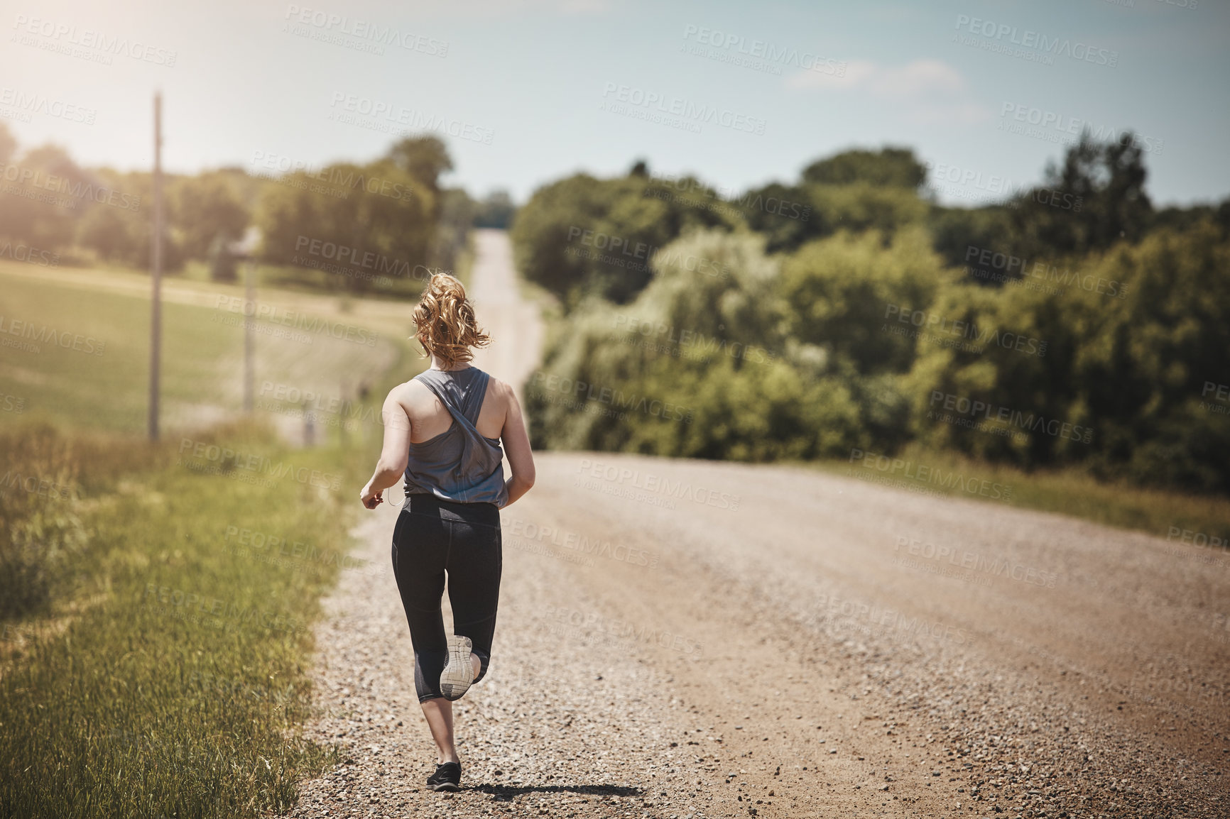 Buy stock photo Rearview shot of a young woman out on a trail run