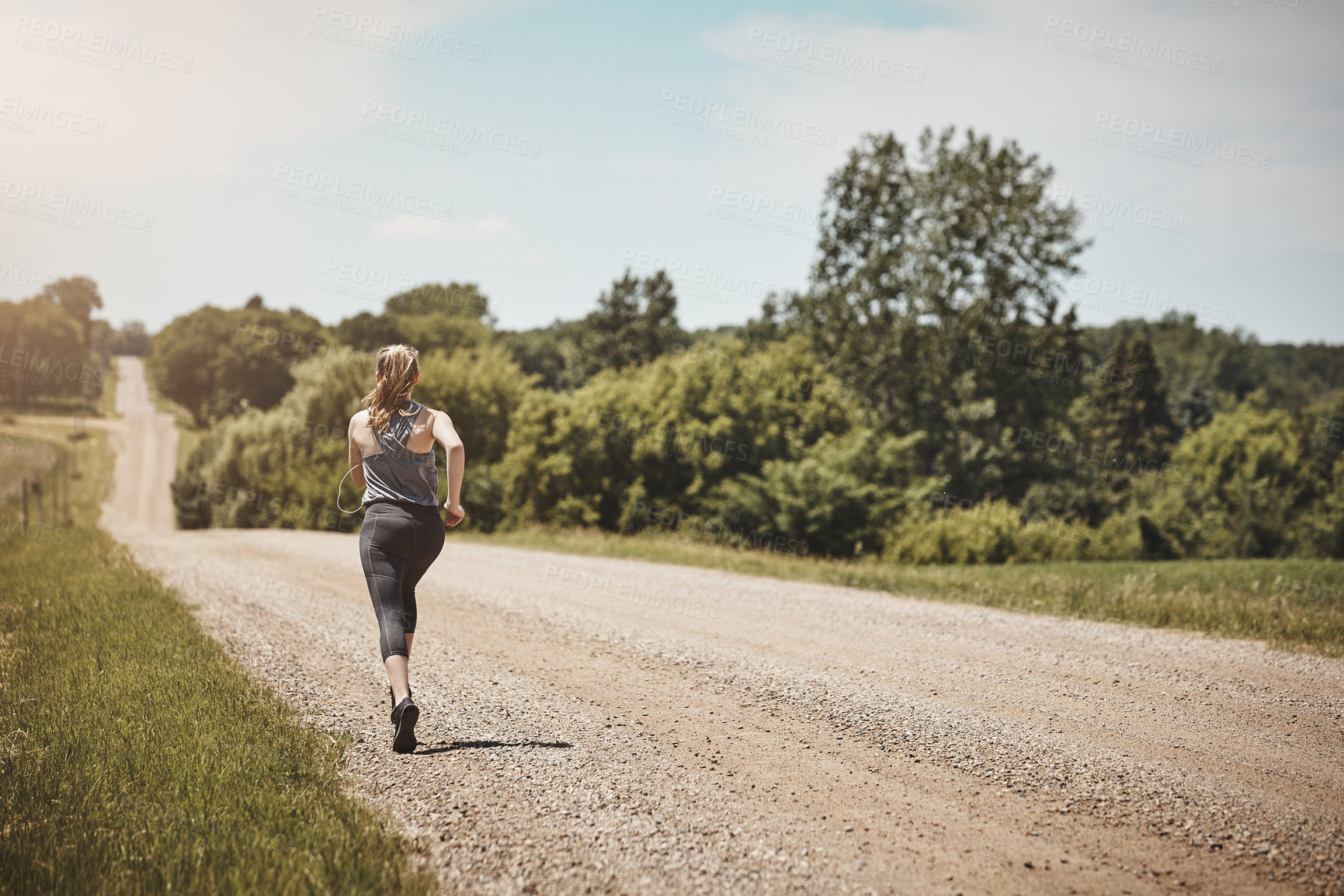 Buy stock photo Rearview shot of a young woman out on a trail run