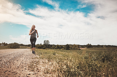 Buy stock photo Shot of a young woman out on a trail run