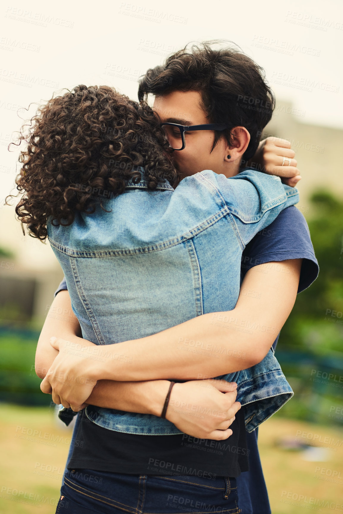 Buy stock photo Cropped shot of a teenage couple embracing each other outdoors
