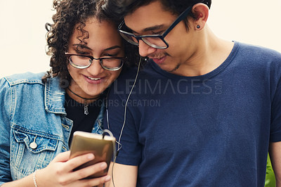 Buy stock photo Cropped shot of a teenage couple listening to music together outdoors