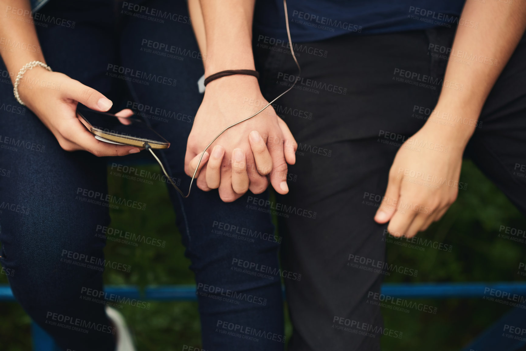 Buy stock photo Cropped shot of an unrecognizable couple listening to music together outdoors