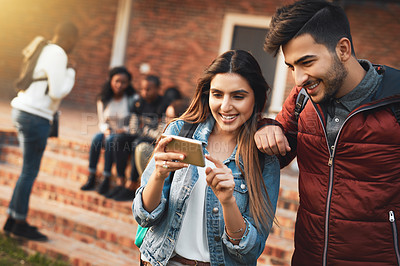 Buy stock photo Shot of a young man and woman using a mobile phone together on campus