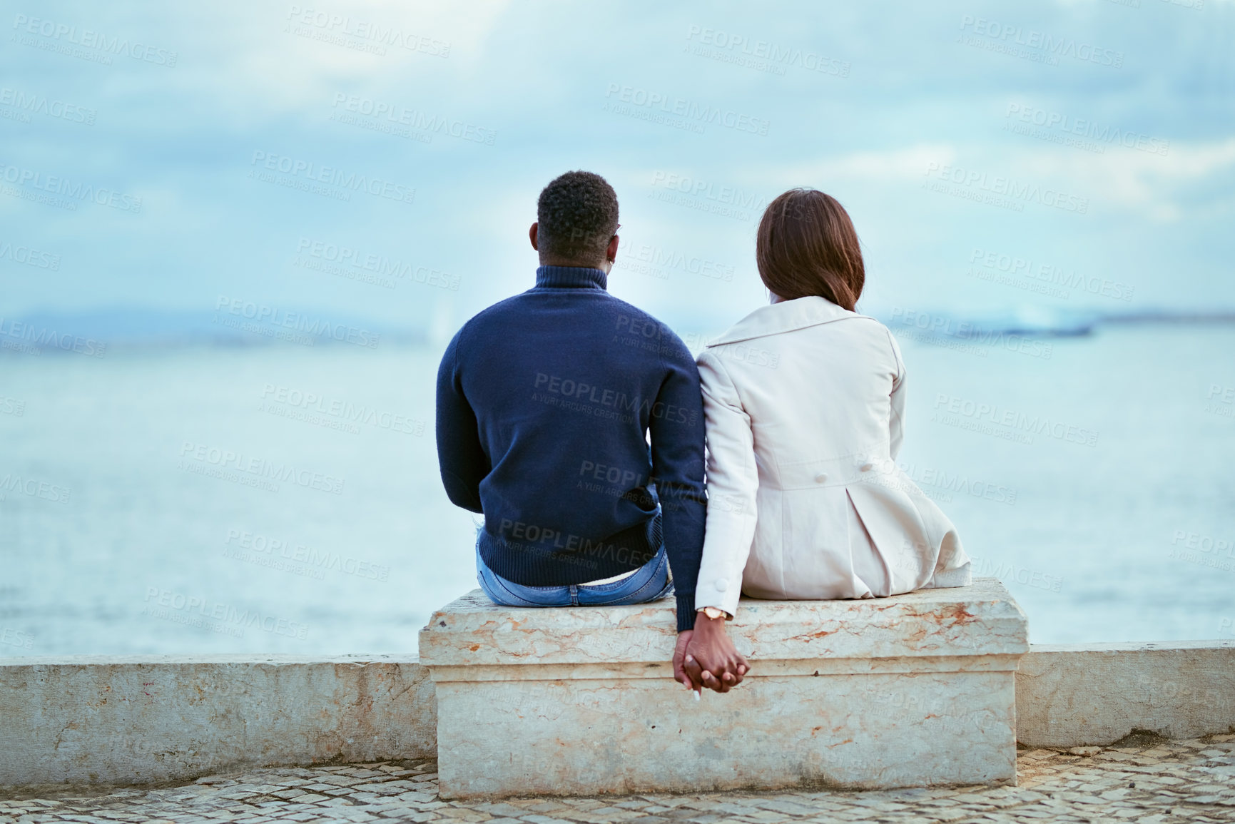Buy stock photo Rearview shot of a young couple looking at the view of the sea outdoors