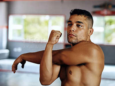 Buy stock photo Cropped shot of a young man stretching before a fight at the gym