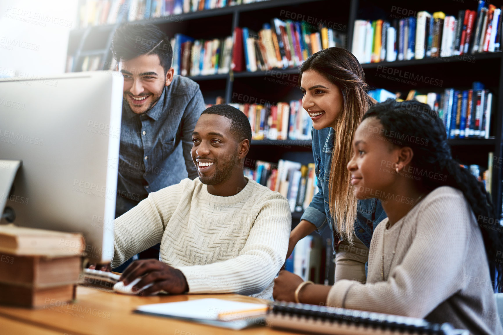 Buy stock photo Shot of a group of young students using a computer together in a college library