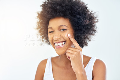 Buy stock photo Cropped shot of an attractive young woman applying moisturizer on her face in the bathroom at home