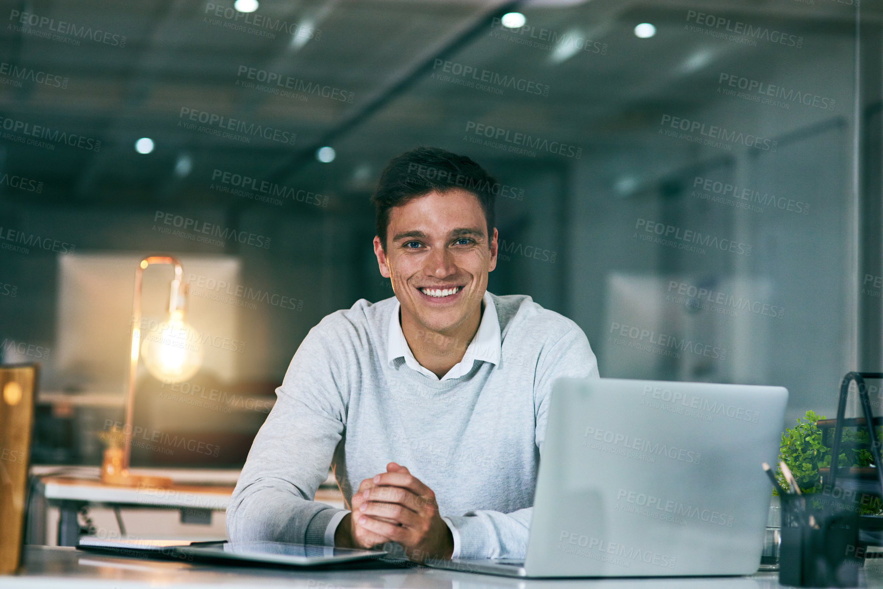 Buy stock photo Portrait of a confident young businessman working in an office at night