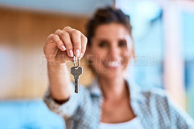 Buy stock photo Portrait of a cheerful young woman holding the keys to her new home while standing inside during the day