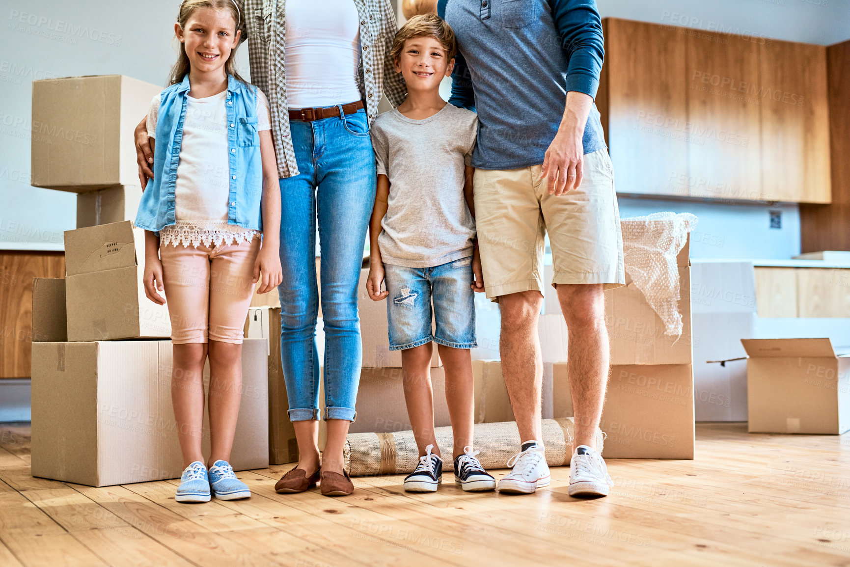 Buy stock photo Portrait of a young brother and sister standing next to their unrecognizable parents inside at home during the day