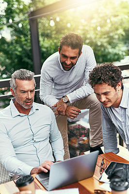 Buy stock photo Shot of a team of colleagues using a laptop together during a meeting outdoors