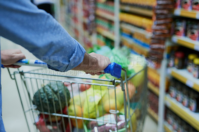Buy stock photo Cropped shot of a man pushing a shopping cart in a grocery store