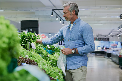 Buy stock photo Shot of a handsome mature man shopping for healthy food in a grocery store