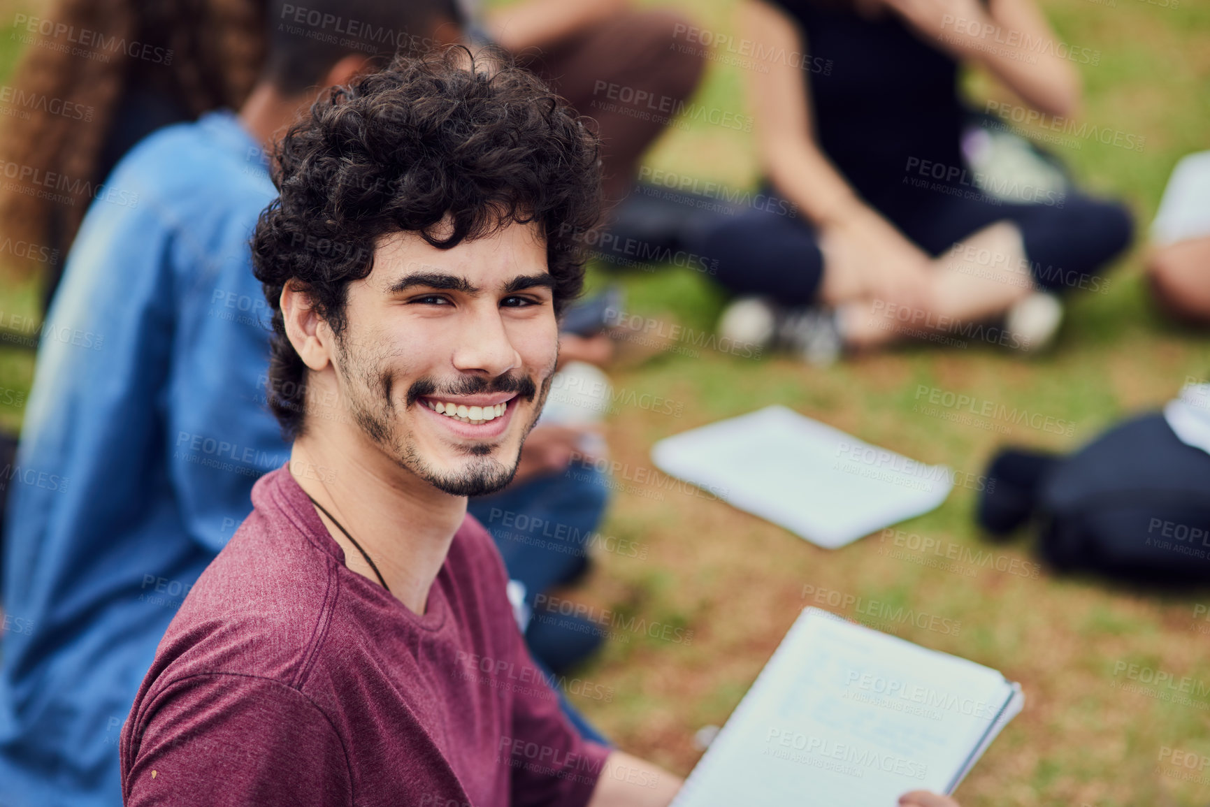 Buy stock photo Portrait of a cheerful young man  sitting in the park with his friends and studying outside during the day