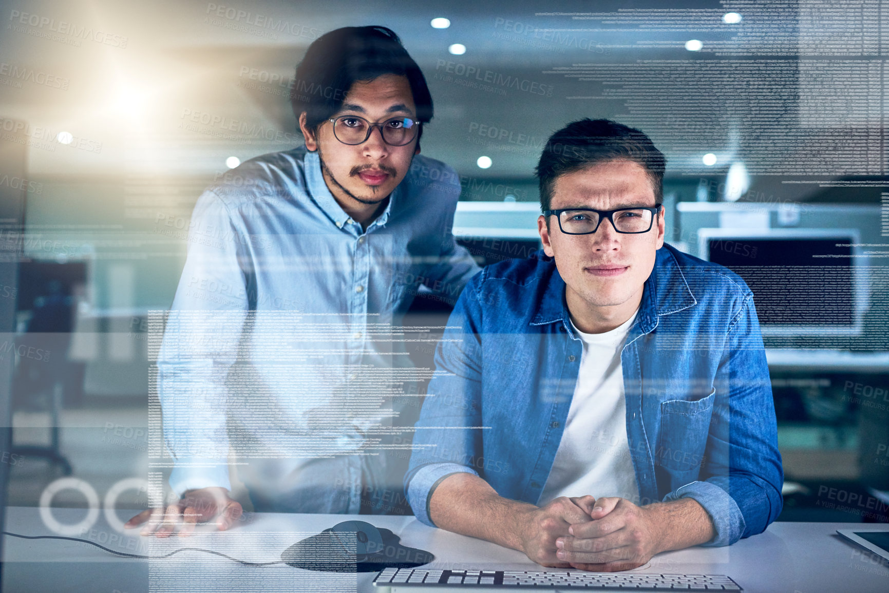 Buy stock photo Portrait of two young male programmers working on a computer together in the office at night