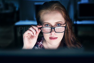Buy stock photo Portrait of a focused young female programmer working on a computer in the office at work during the night