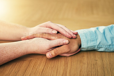 Buy stock photo Cropped shot of a man and woman holding hands in comfort on a table