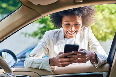 Buy stock photo Shot of a cheerful young businesswoman browsing on her cellphone while on her way to get into her car to go to work