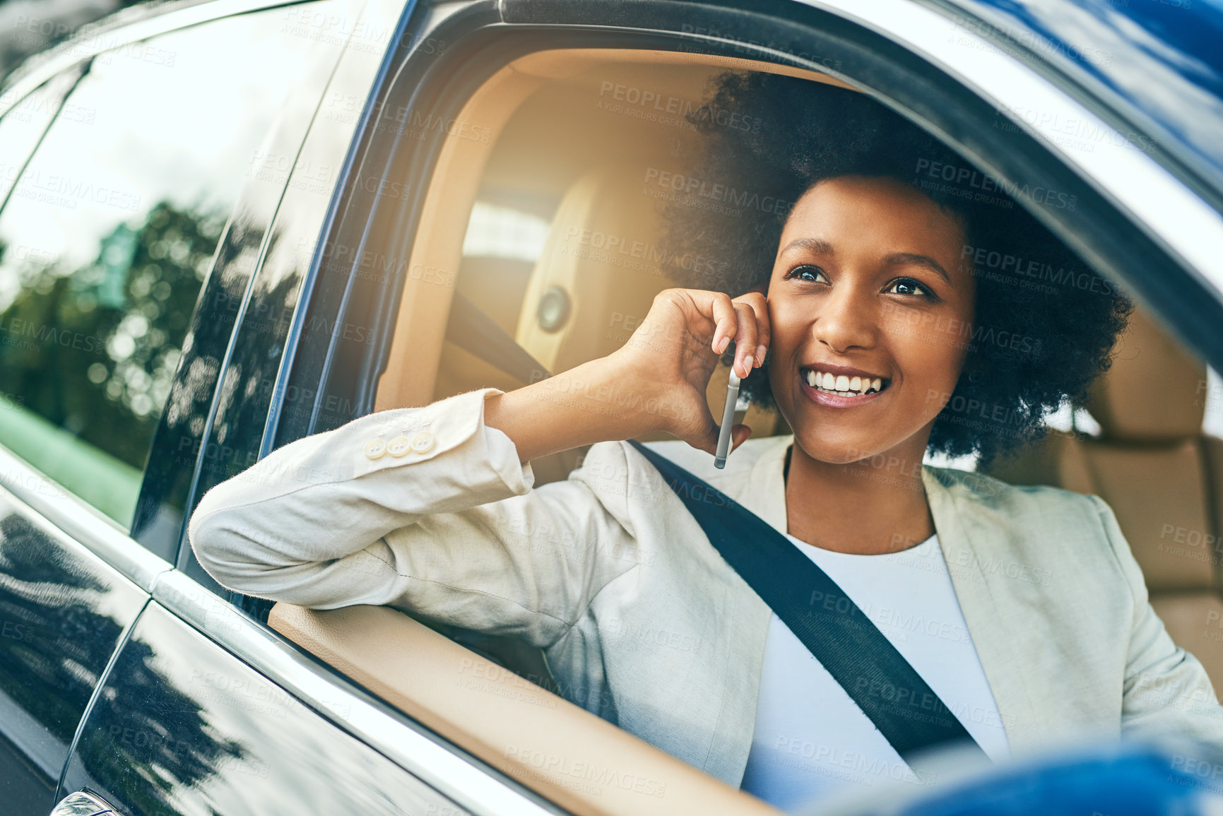 Buy stock photo Shot of a cheerful young businesswoman driving in a car on her way to work while talking on a cellphone during the day