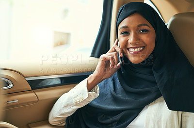 Buy stock photo Portrait of a cheerful young businesswoman talking on her mobile phone while being seated in the back of a car on her way to work