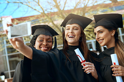 Buy stock photo Shot of a group of young women taking selfies with a mobile phone on graduation day