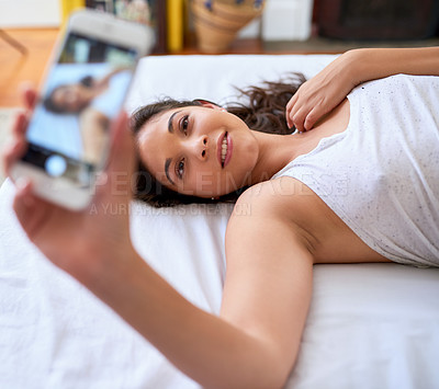 Buy stock photo Shot of a beautiful young woman taking selfies on her bed at home