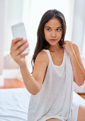 Buy stock photo Shot of a beautiful young woman taking selfies on her bed at home