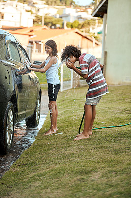 Buy stock photo Shot of two cheerful children washing their parent's car together outside during the day