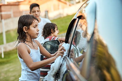 Buy stock photo Shot of a group of cheerful young kids washing their parents car together outside during the day