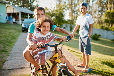 Buy stock photo Shot of happy young brothers riding a bicycle together in their backyard