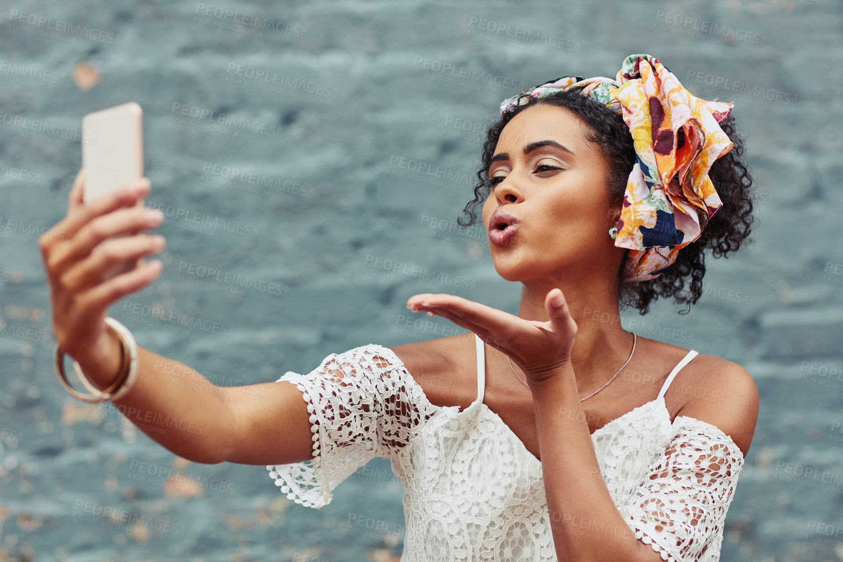 Buy stock photo Cropped shot of an attractive young woman taking a selfie against a brick wall outside