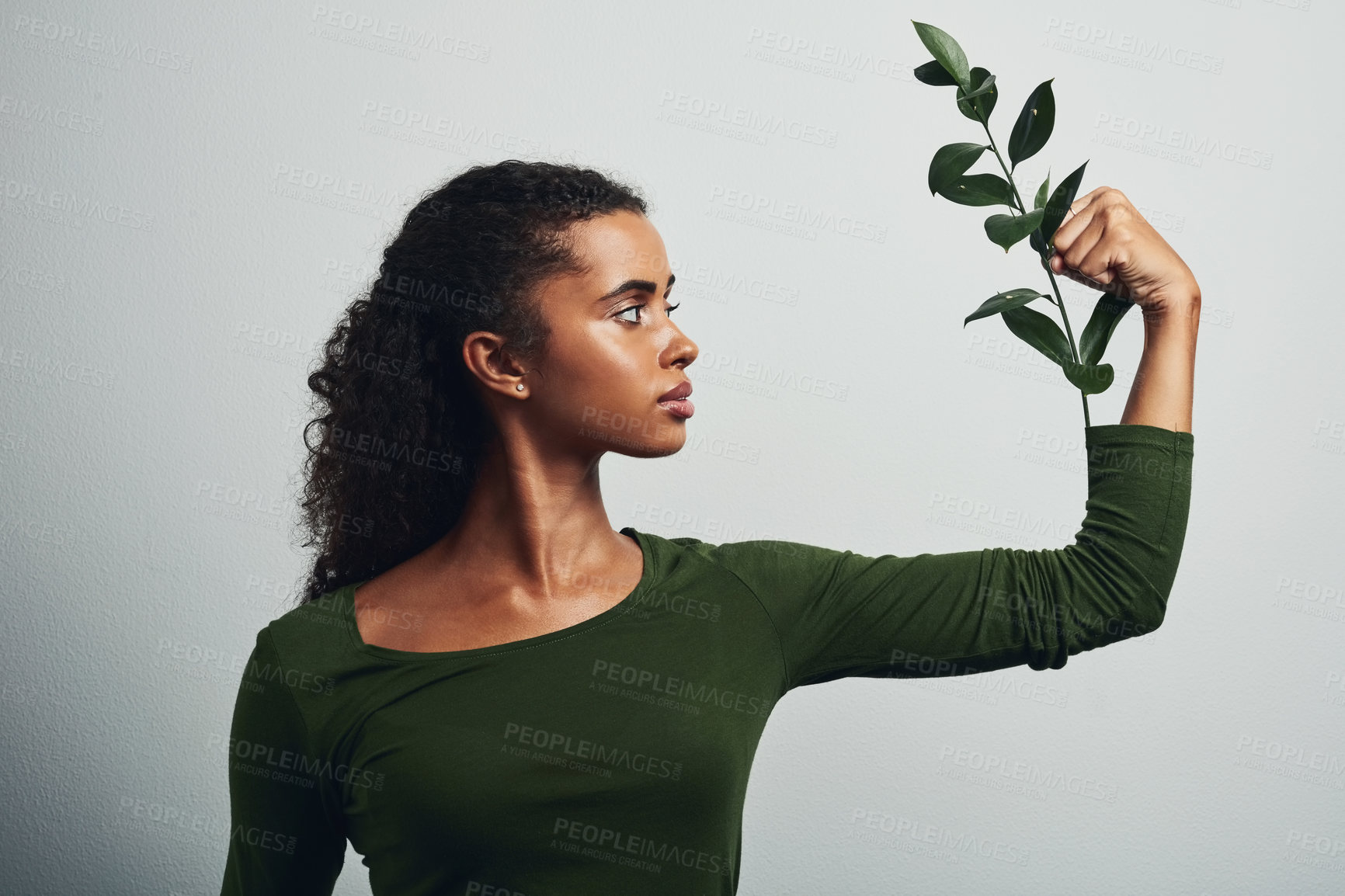 Buy stock photo Studio shot of an attractive young woman posing with a plant against a grey background