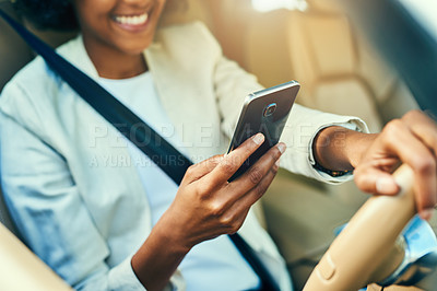 Buy stock photo Shot of an unrecognizable businesswoman browsing on her mobile phone while driving in a car during the day