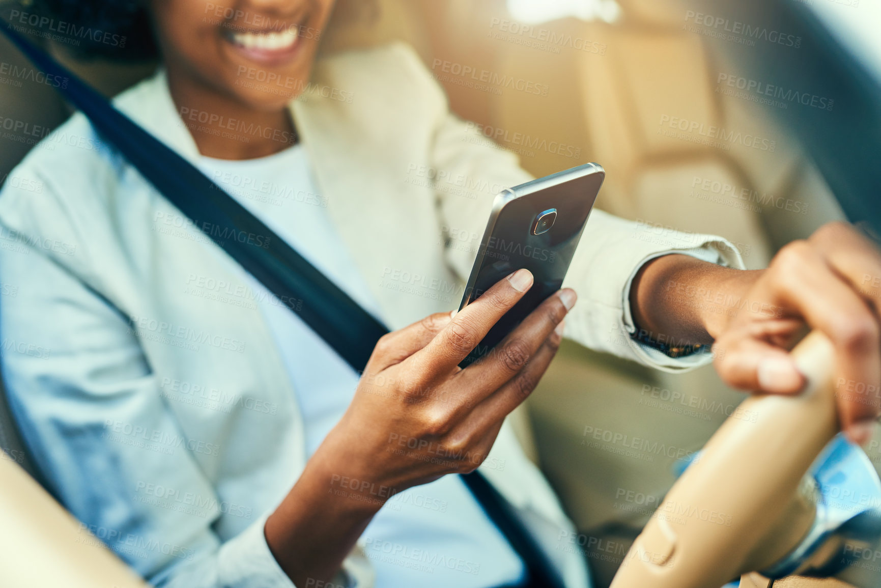 Buy stock photo Shot of an unrecognizable businesswoman browsing on her mobile phone while driving in a car during the day