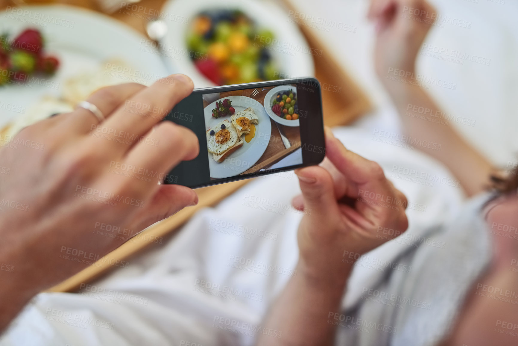 Buy stock photo PoV shot of an unrecognizable couple taking a photo of their breakfast that they're having in bed during morning hours