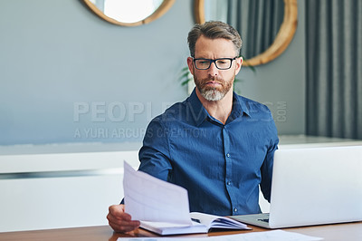 Buy stock photo Shot of a focussed middle aged businessman sorting out documents and working from home during the day