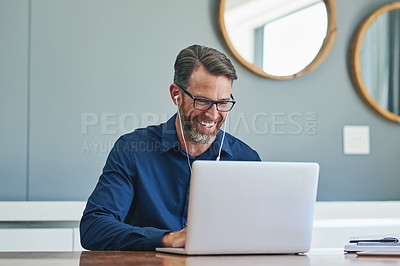 Buy stock photo Shot of a cheerful middle aged businessman making a Skype call on his laptop at home during the day
